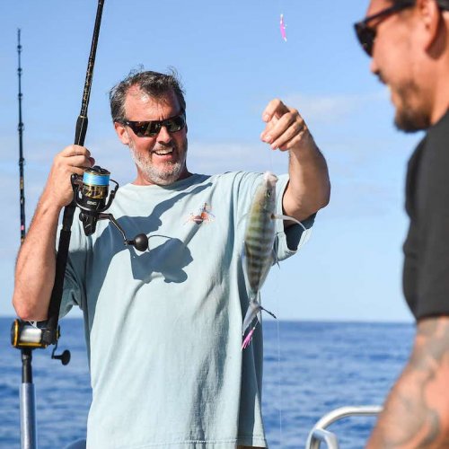 Angler holding his catch aboard The VENTURE Boat